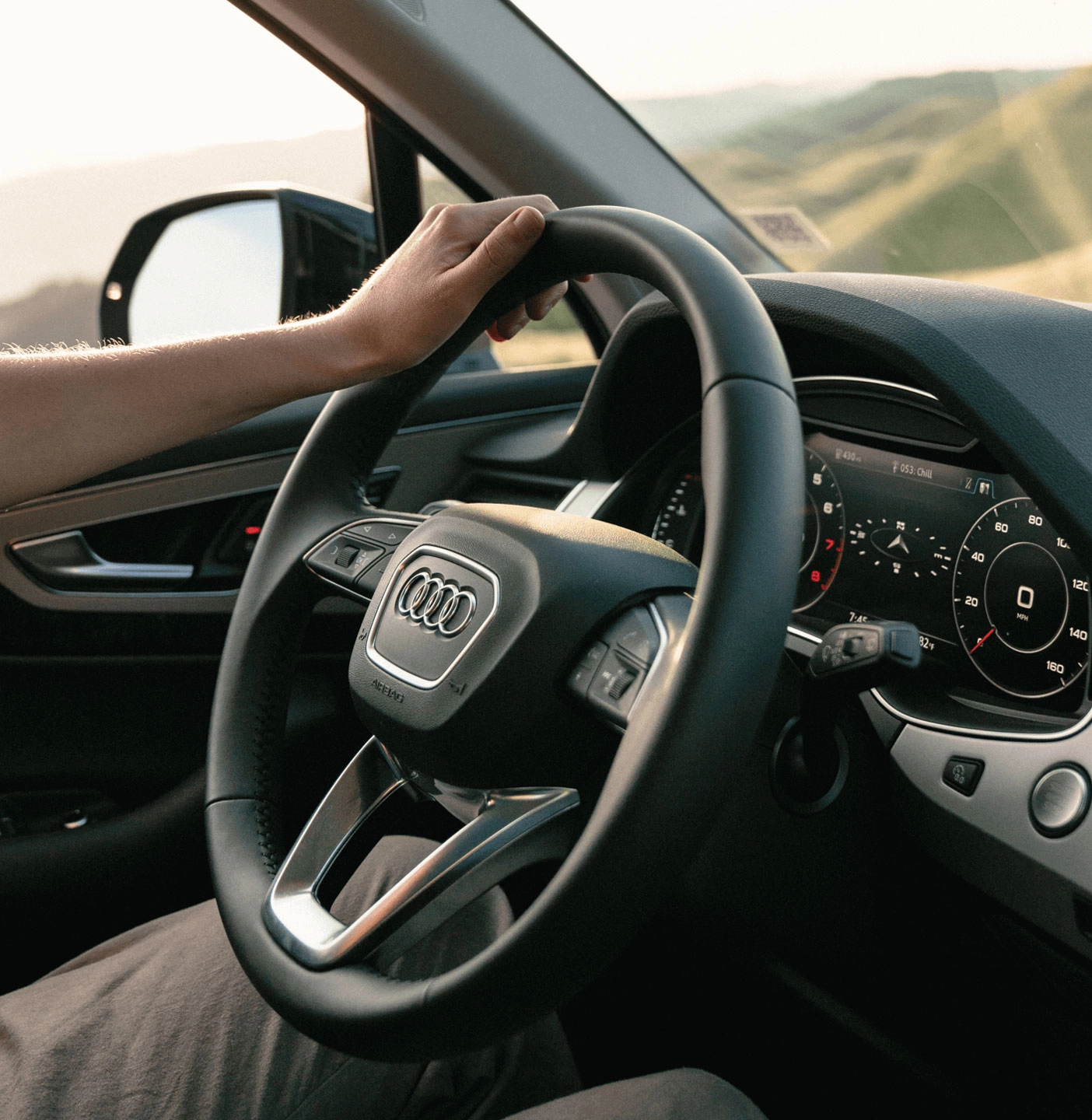 The steering wheel and dashboard of an Audi while someone is driving