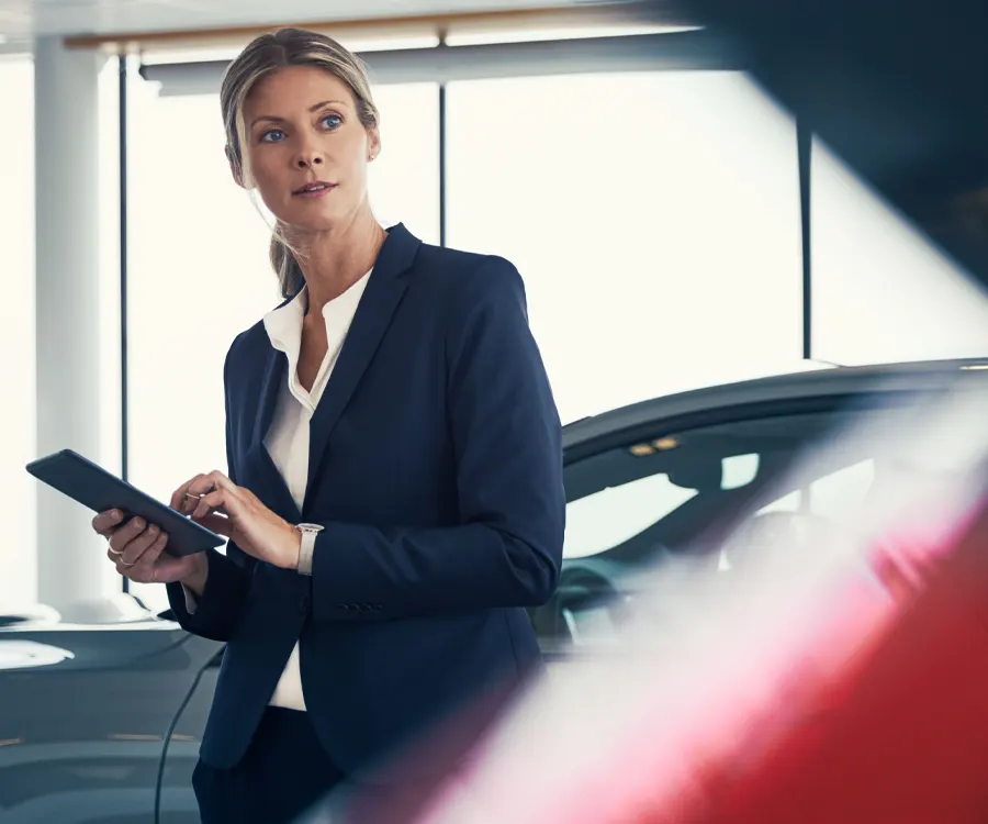 Volvo Sales Consultant looking at vehicle with tablet taking notes