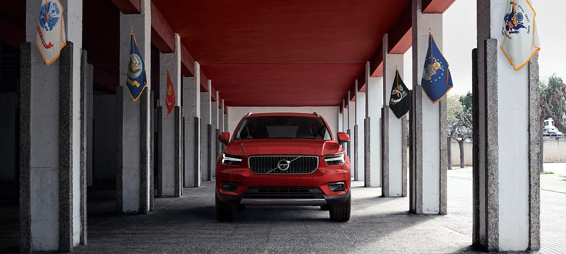 US Military Red Volvo driving through sidewalk with flags