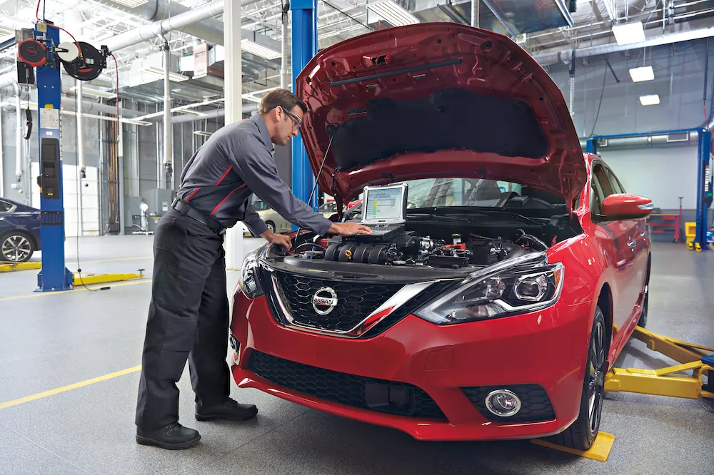 Certified Serviice Technician running diagnostics on a Nissan Maxima