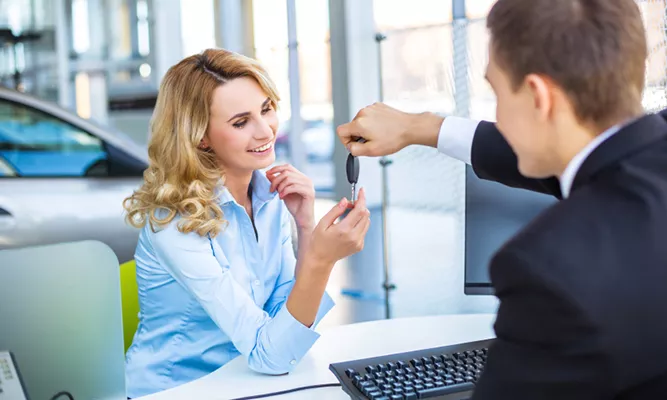 Man handing a smiling blonde woman a set of keys