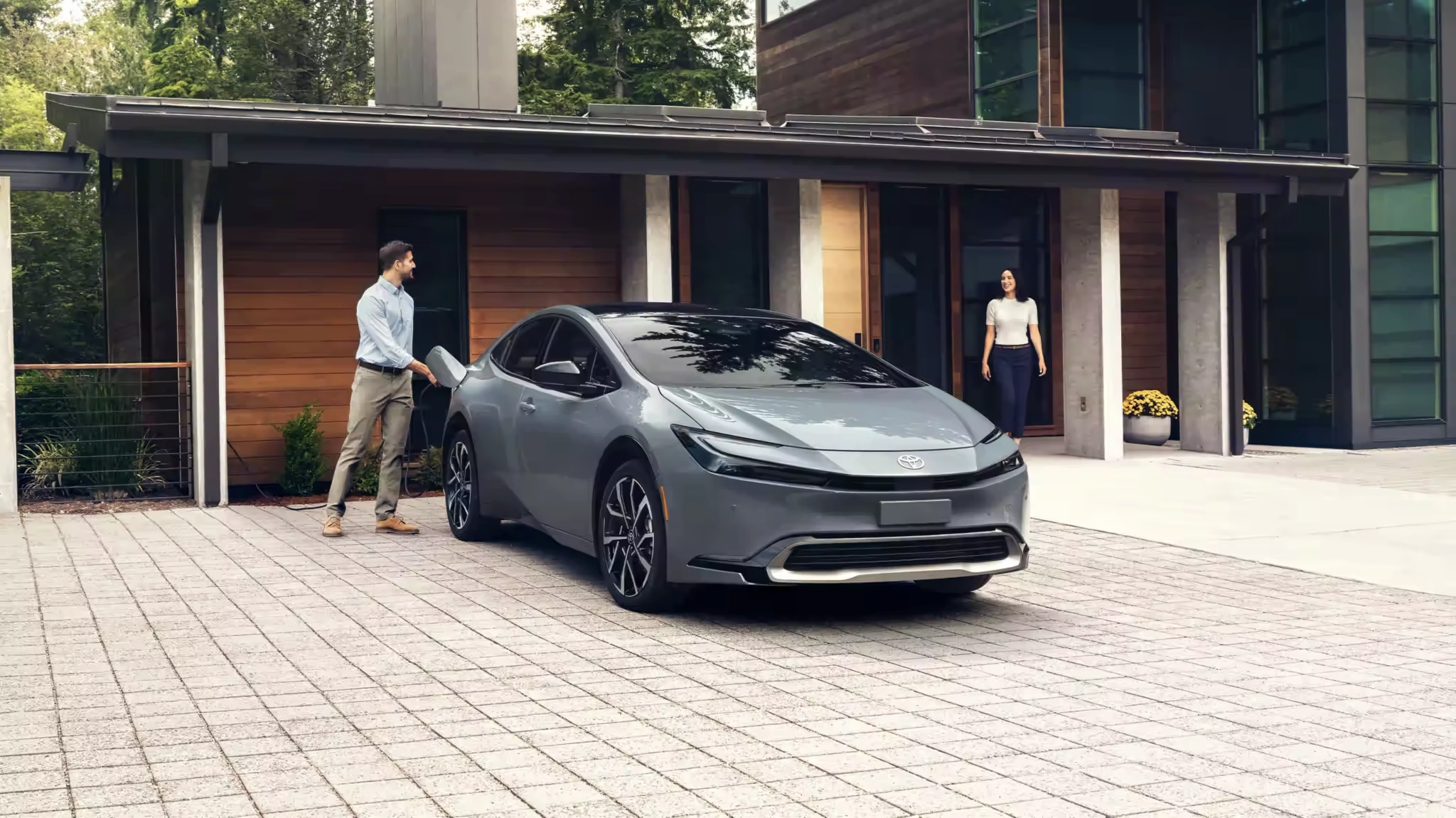 A man talking to a women while charging the Premium Guardian Gray Prius Prime XSE.