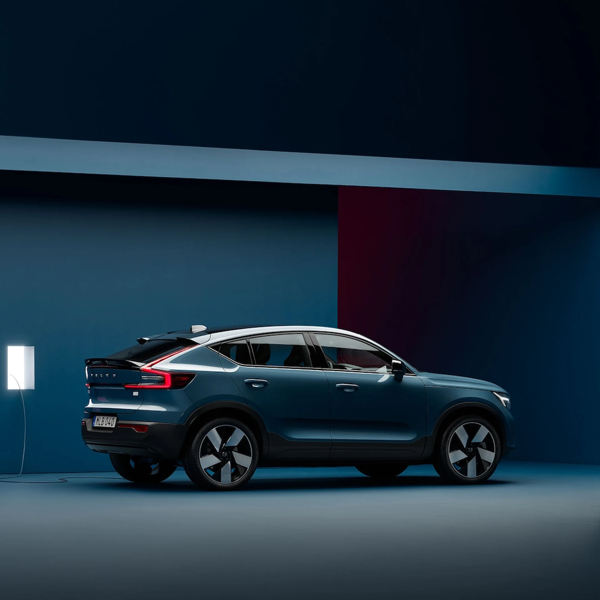 2023 C40 Recharge The side profile of a Fjord Blue Volvo C40 Recharge plugged into charging station