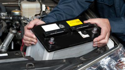 mechanic replacing battery in vehicle