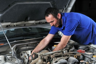 mechanic working in engine bay of vehicle