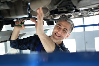 mechanic inspecting bottom of a vehicle
