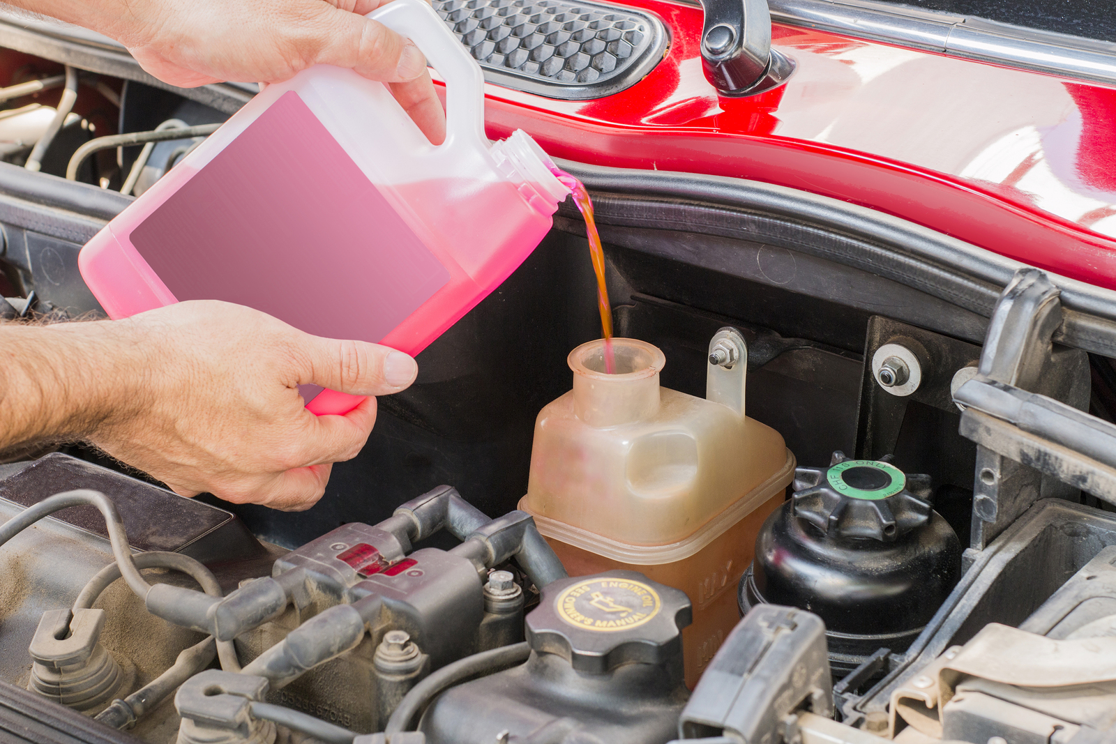mechanic topping off vehicle's coolant reservoir