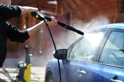 person washing vehicle with a power washer