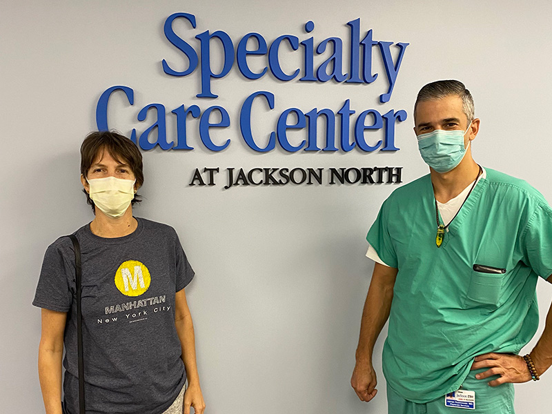 一名医生和一名妇女站在一个牌子前，牌子上写着北杰克逊专科护理中心