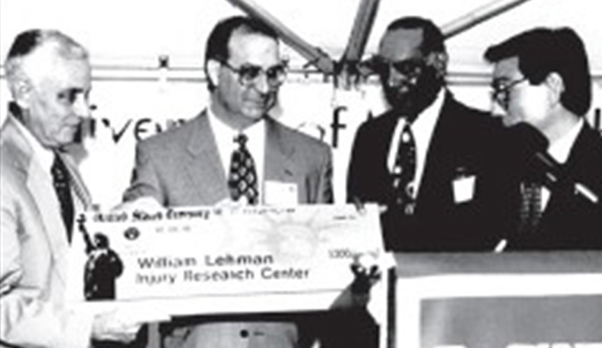 四个男人拿着一张大支票站在讲台前的黑白图像