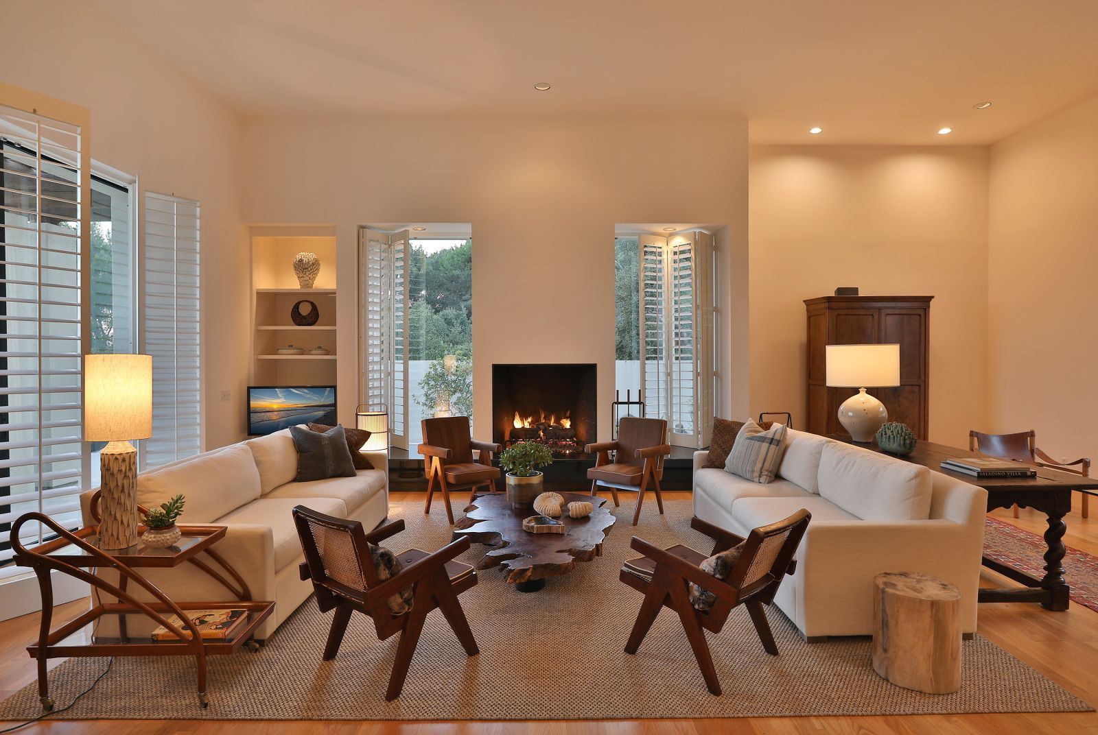 The pristine living room with lit fireplace of a modern estate for lease.