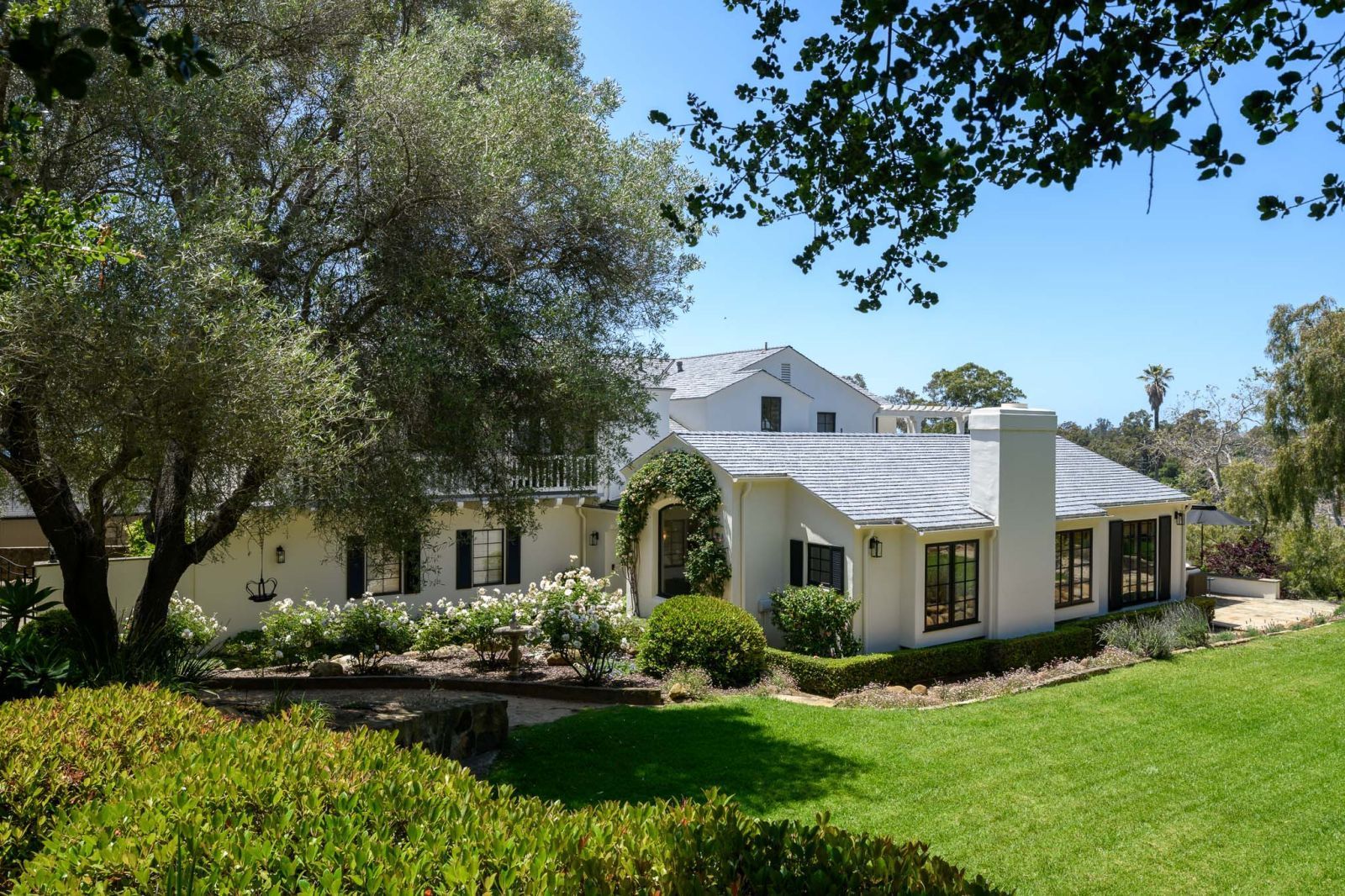 A California coastal 2-story Modern home for lease, with large trees and lawn.