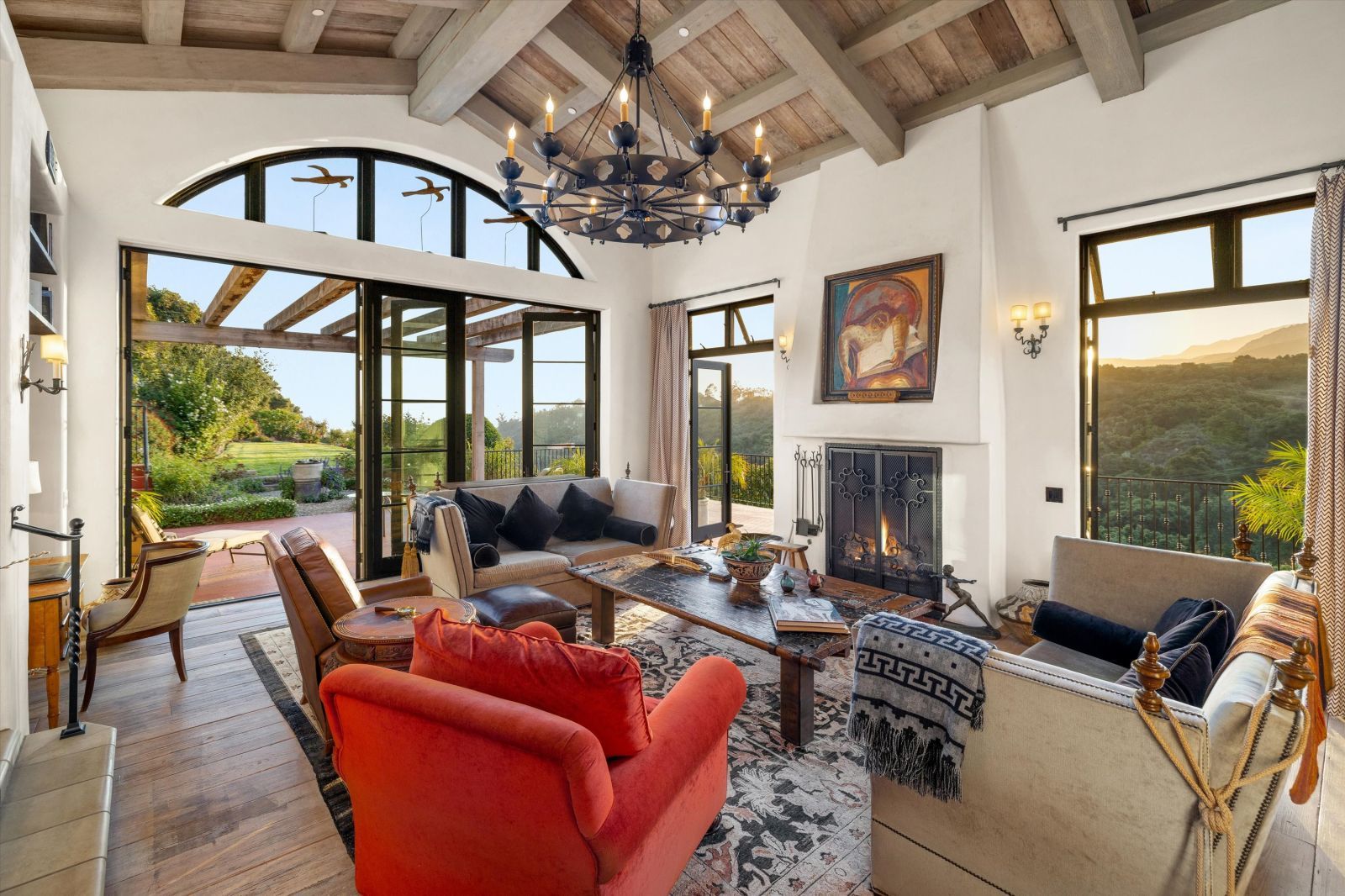 A lbeautifully furnished uxury living room with a fireplace and lots of natural light streaming through the windows and open doors.