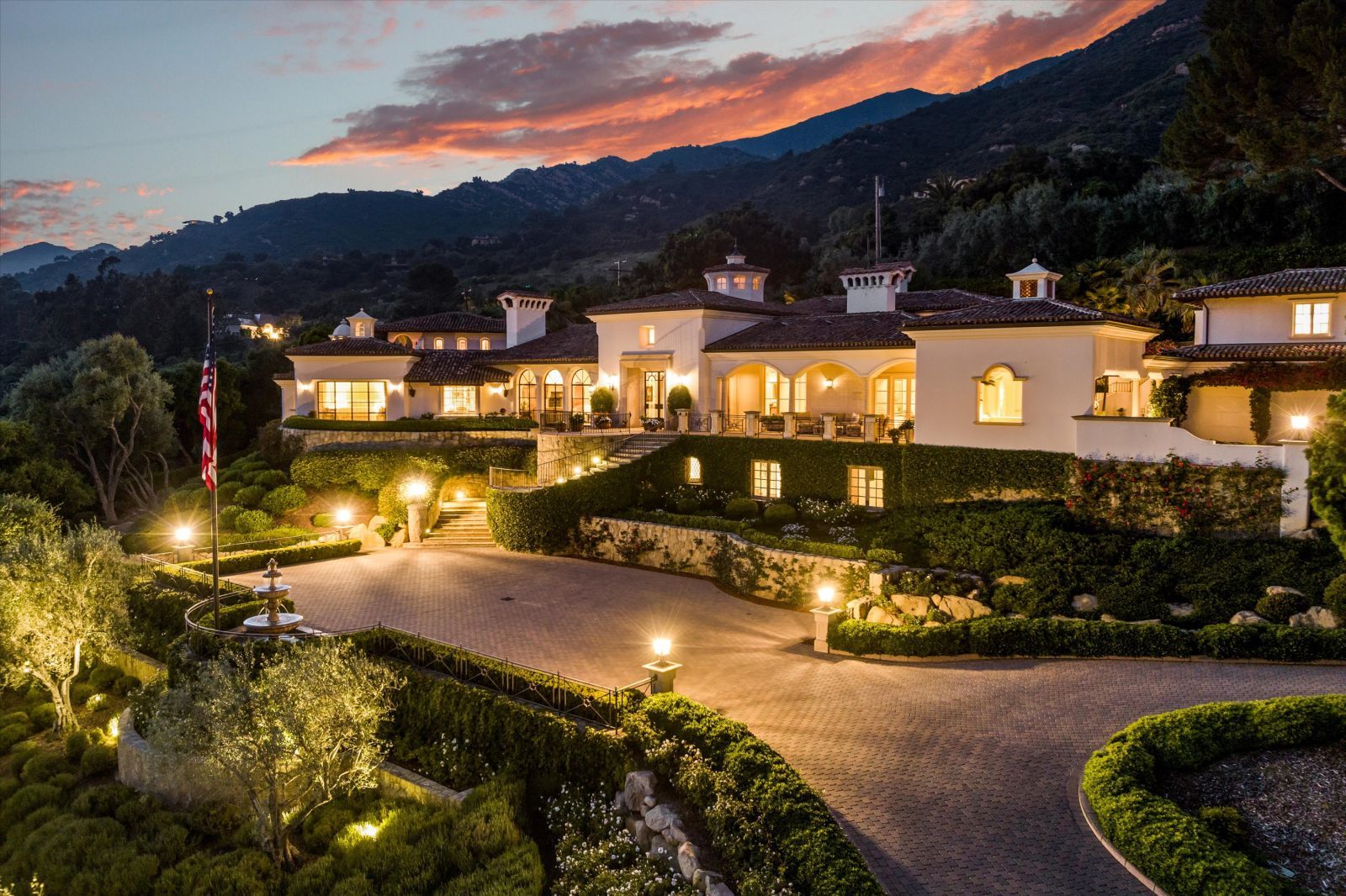 The lights are on in this front view of a home at dusk with a beautiful sky