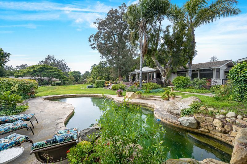 A lovely Hope Ranch ranch-style home with a pool in the foreground surrounded by lush landscaping.