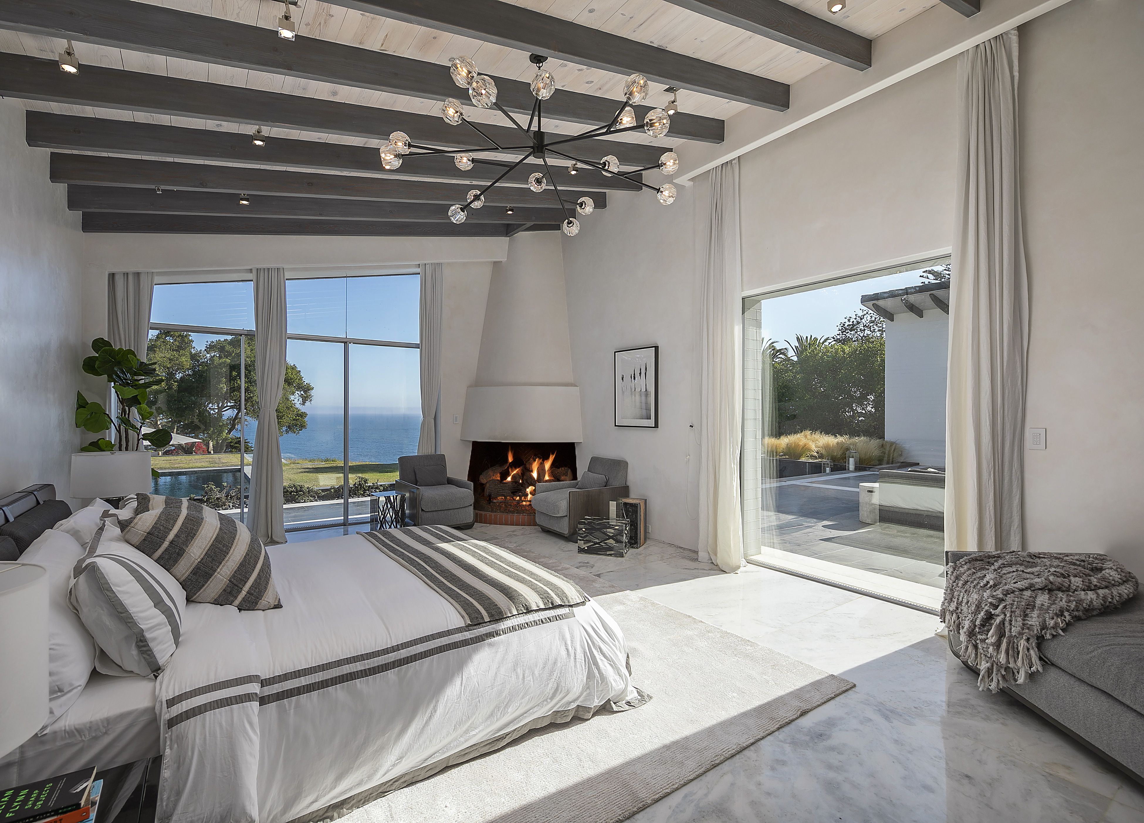 Primary bedroom of a Hope Ranch home, with open-beam ceiling, fireplace and expansive ocean and garden views