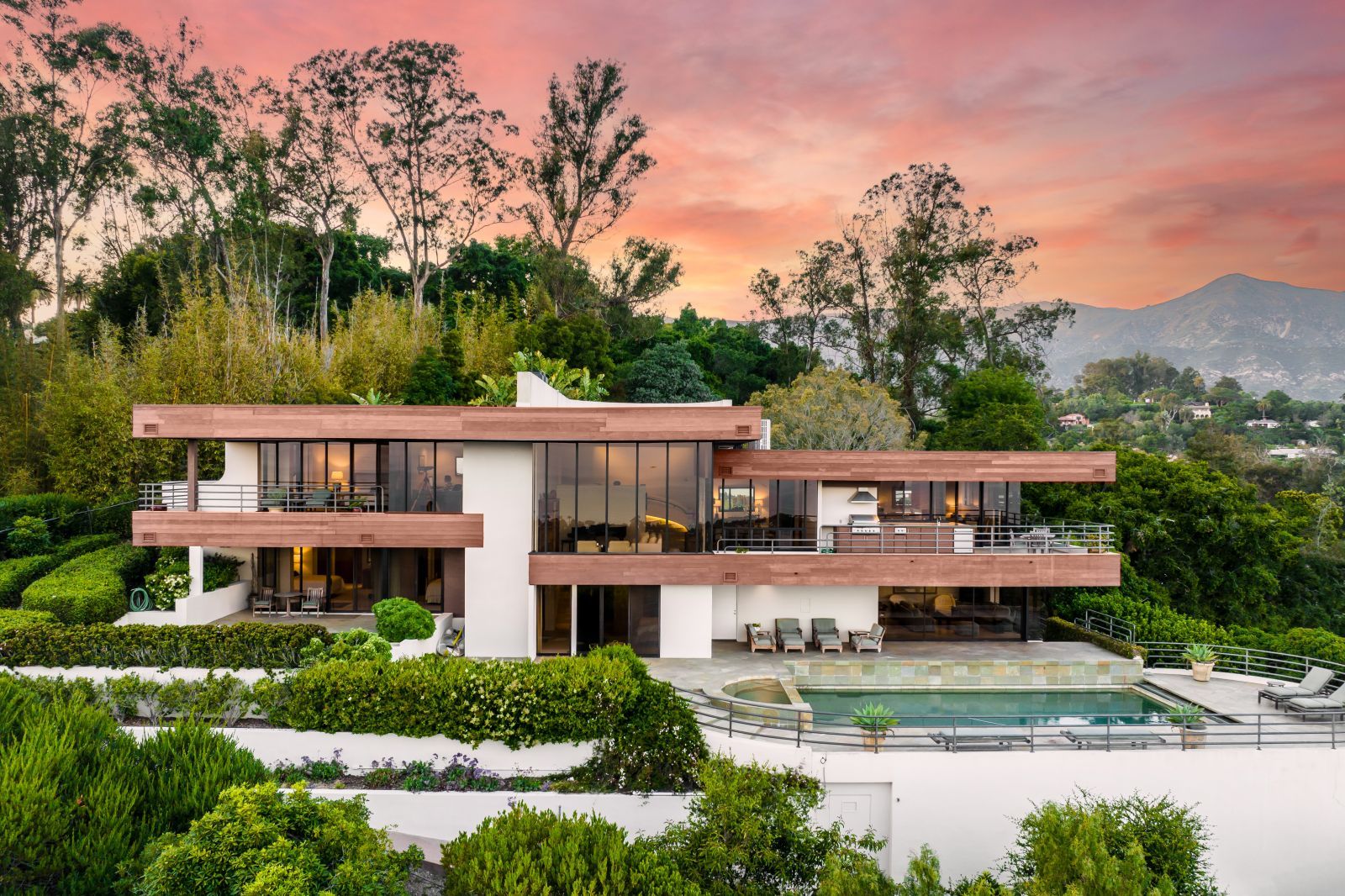 The front of a dramatic contemporary home surrounded by a spectacular sunset in the background