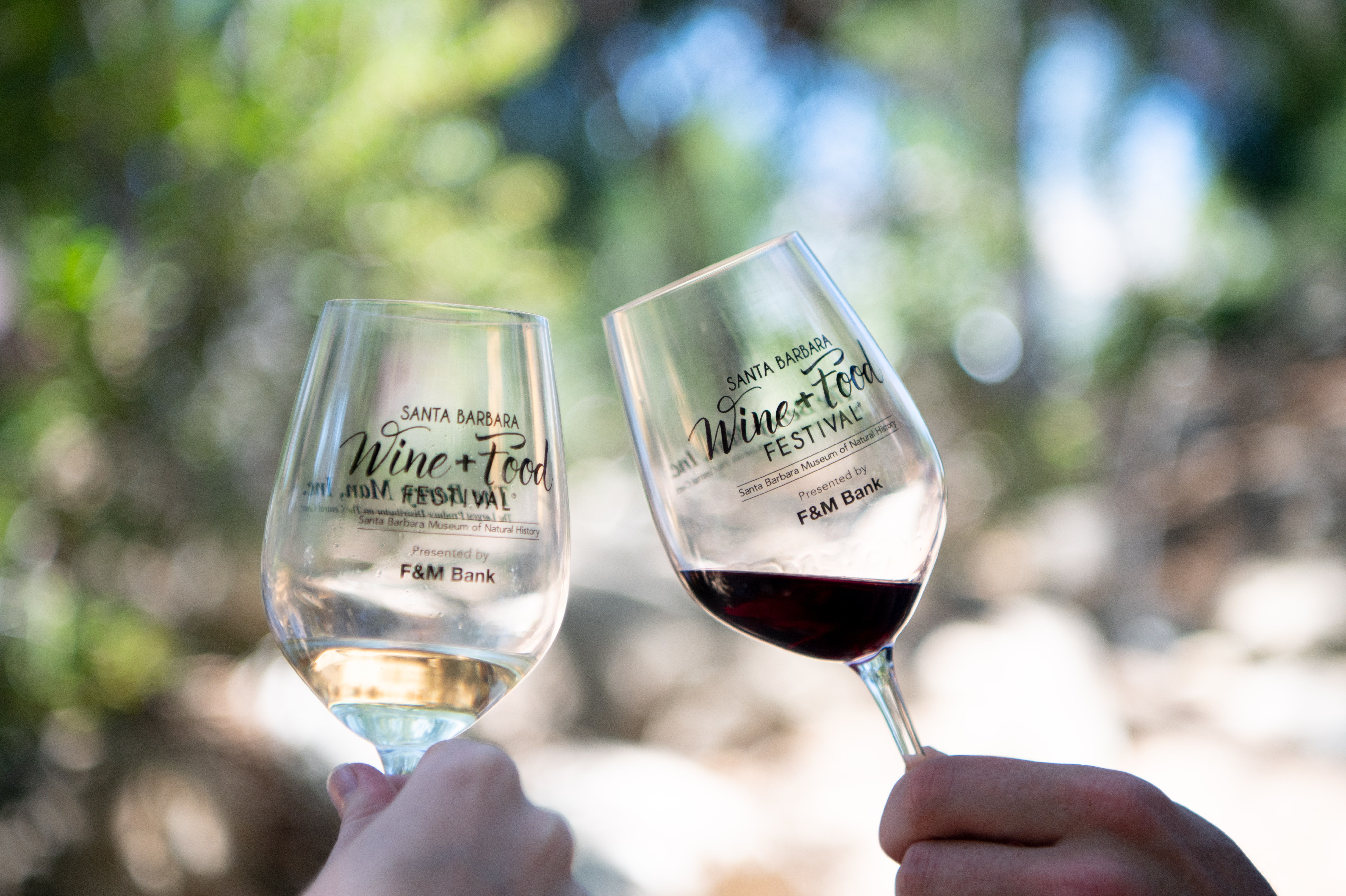 2 people holding wine glasses and toasting at the Santa Barbara Wine + Food Festival®