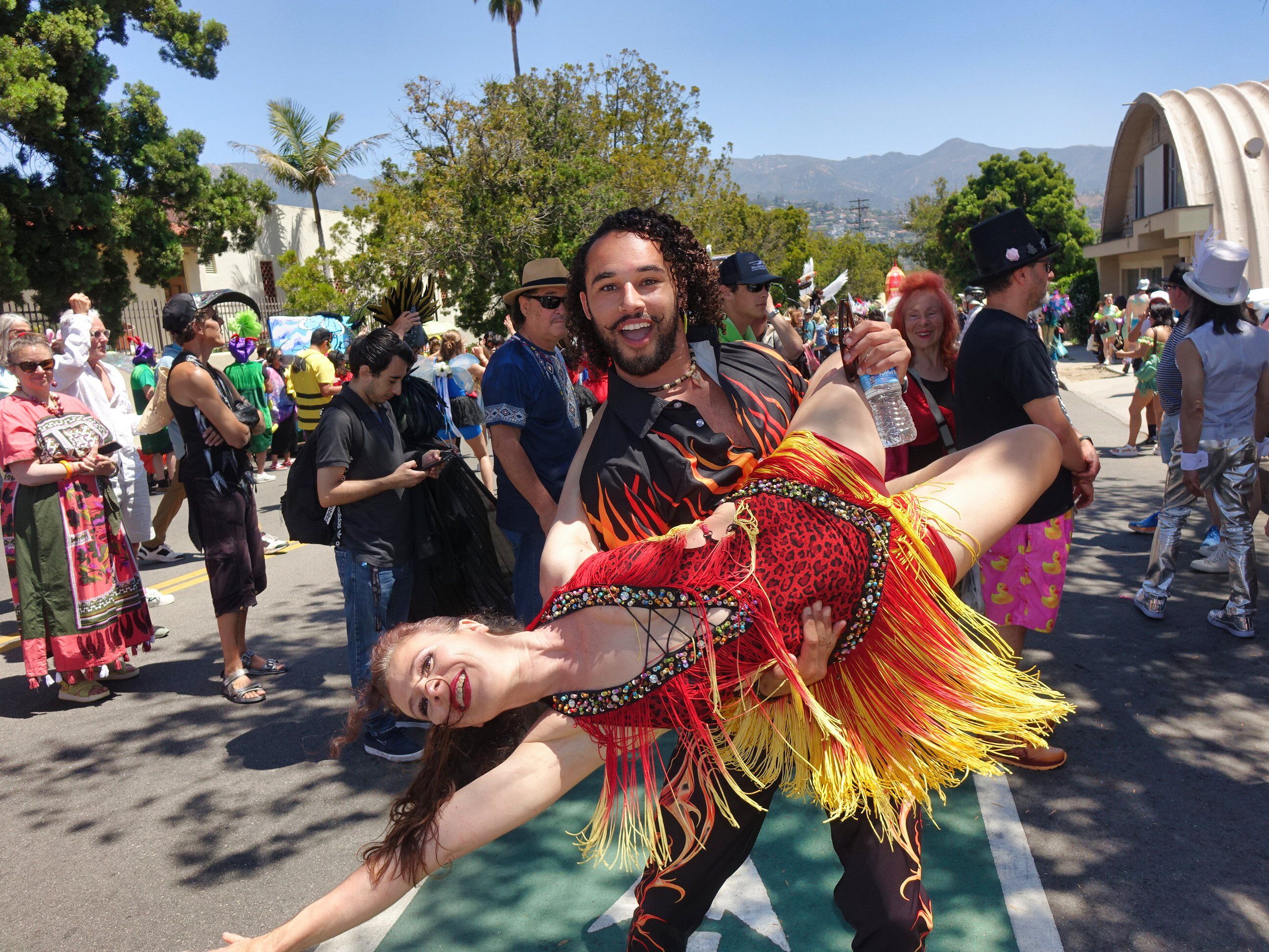 A couple dancing in colorful costumes in the street at the Santa Barbara Summer Solstice Parade.