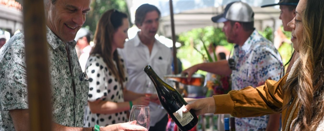 People enjoying themselves at a wine festival outside.
