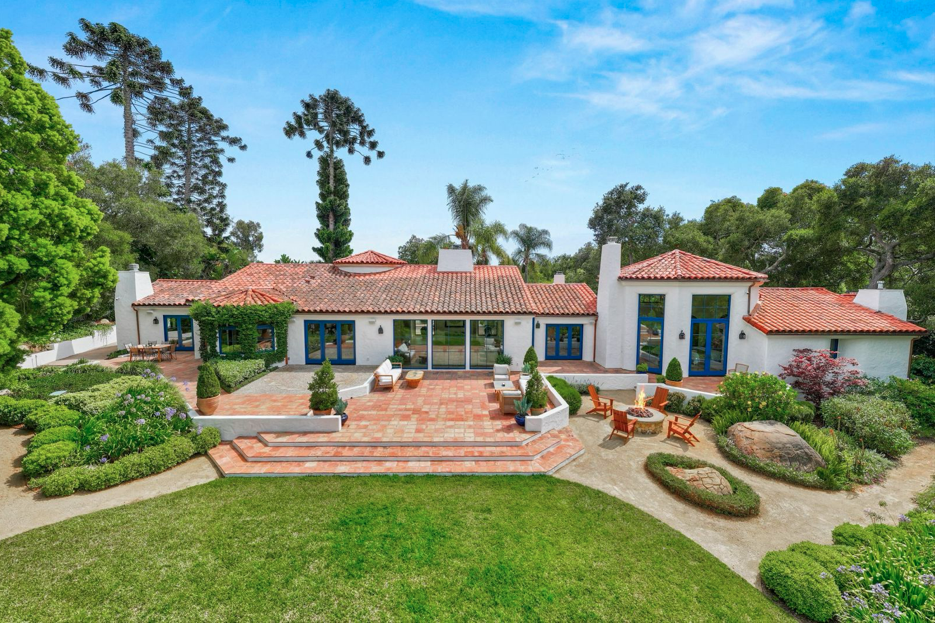 A luxury home with a red tiled roof surrounded by green grass and a red tile terrace.