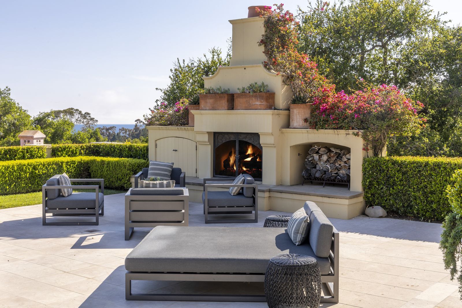 The luxury outdoor living space of a Mediterranean Montecito estate, with a fireplace, luxurious chairs and a lounge