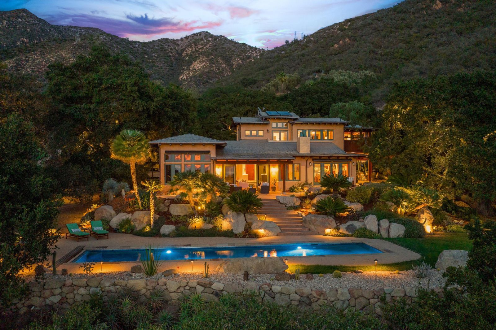 Dusk shot of a Santa Barbara Ocean View home with mountains and green trees in the background.