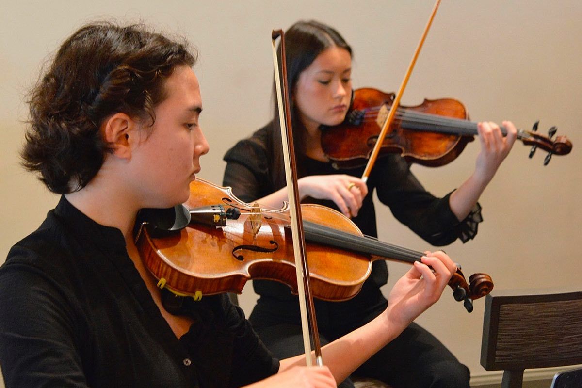 Two young musicians playing violins in The Community Arts Music Association's CAMA's educational program.