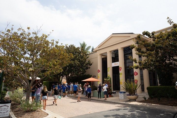 The facade of a building with columns in Santa Barbara with people milling about in front of it.