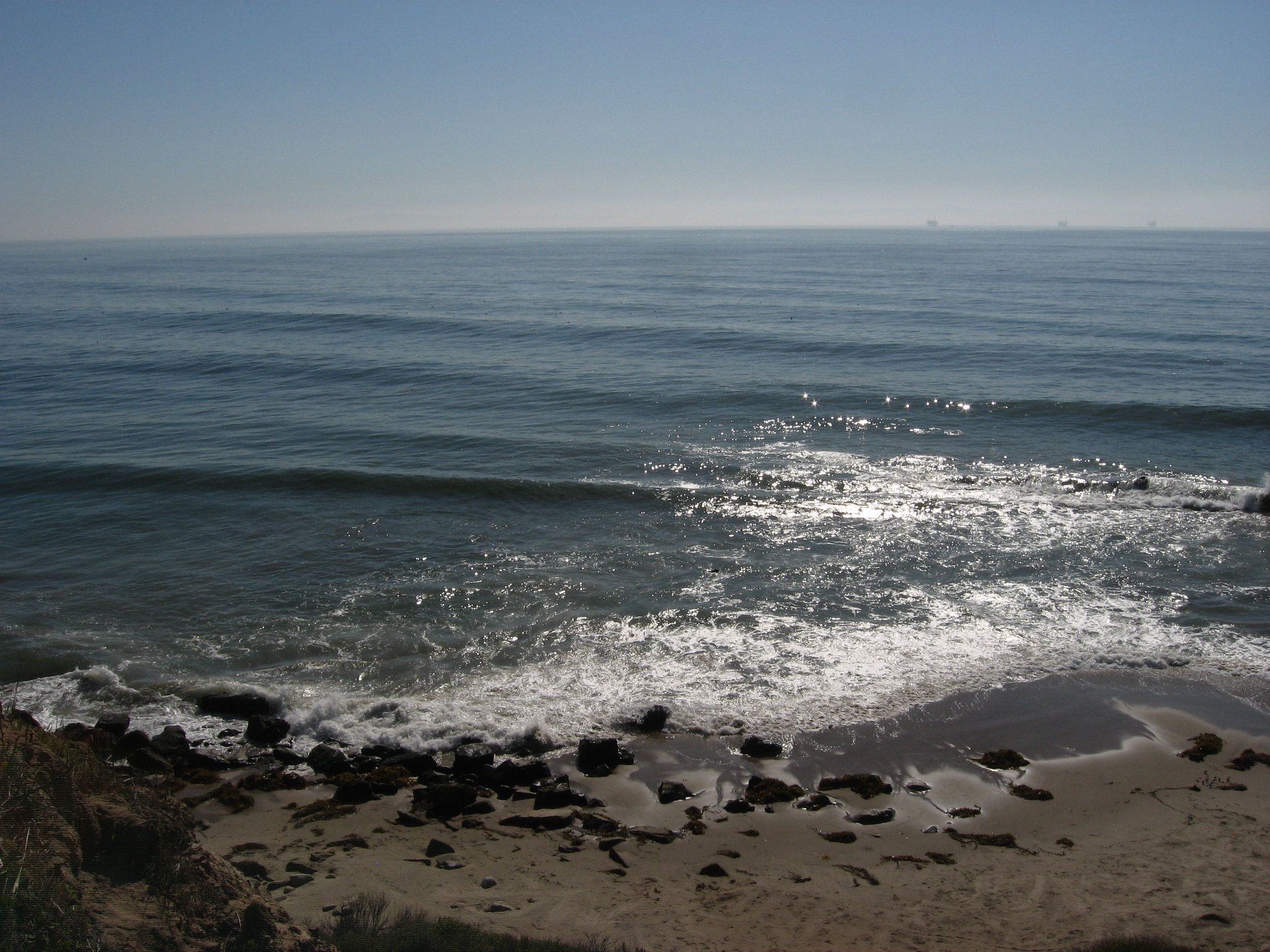 The sparkling shoreline at Carpinteria Bluffs with a gentle wave crashing on the sane