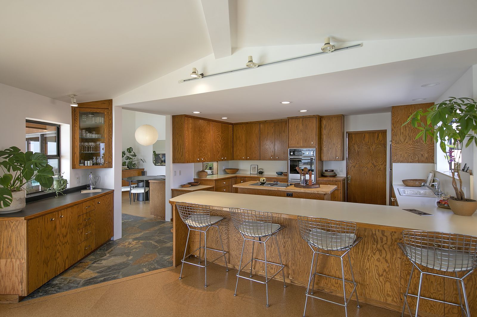 A luxury kitchen with a dining island and stools in the foreground and custom cabinetry in the background.