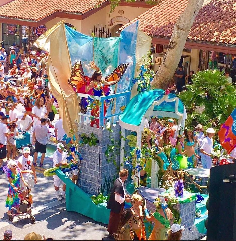 A bright-colored and very festive float making it's way down the street with a crowd cheering it on at the Santa Barbara Summer Solstice Parade.