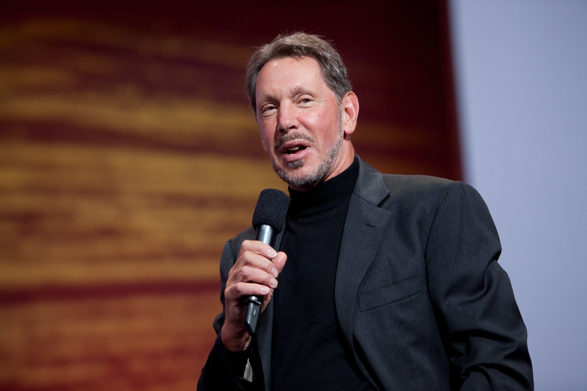 Larry Ellison, the co-founder of Oracle, speaking through a microphone in his hand