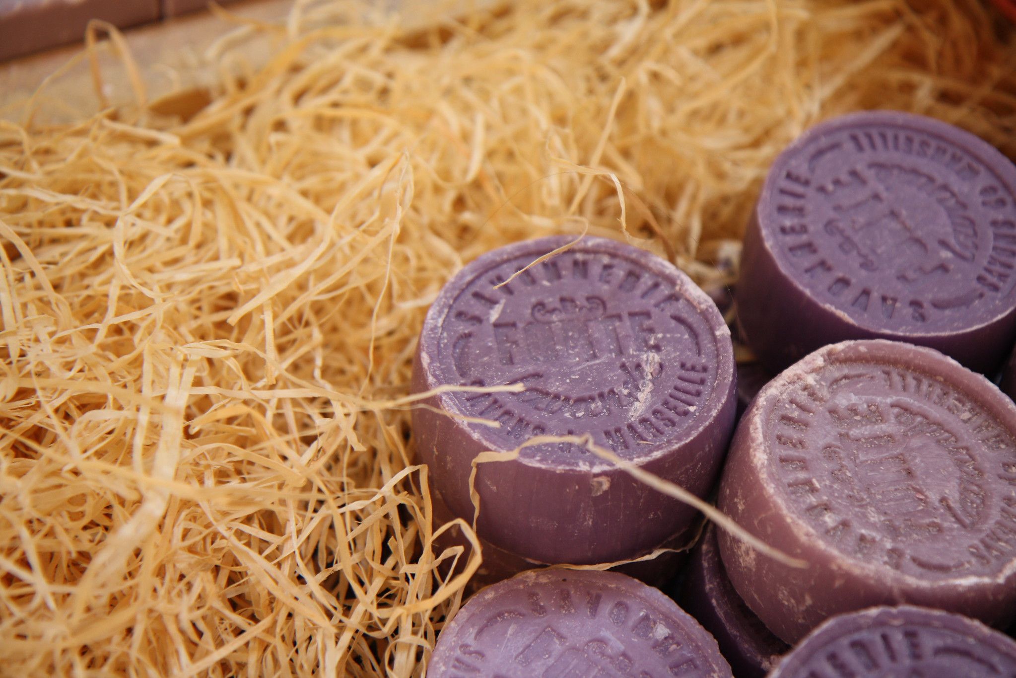 Round bars of lavender soap in a bed of straw.
