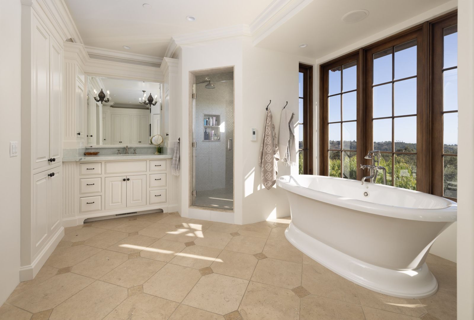 A luxury bathroom with a soaking tub next to a wall of windows.
