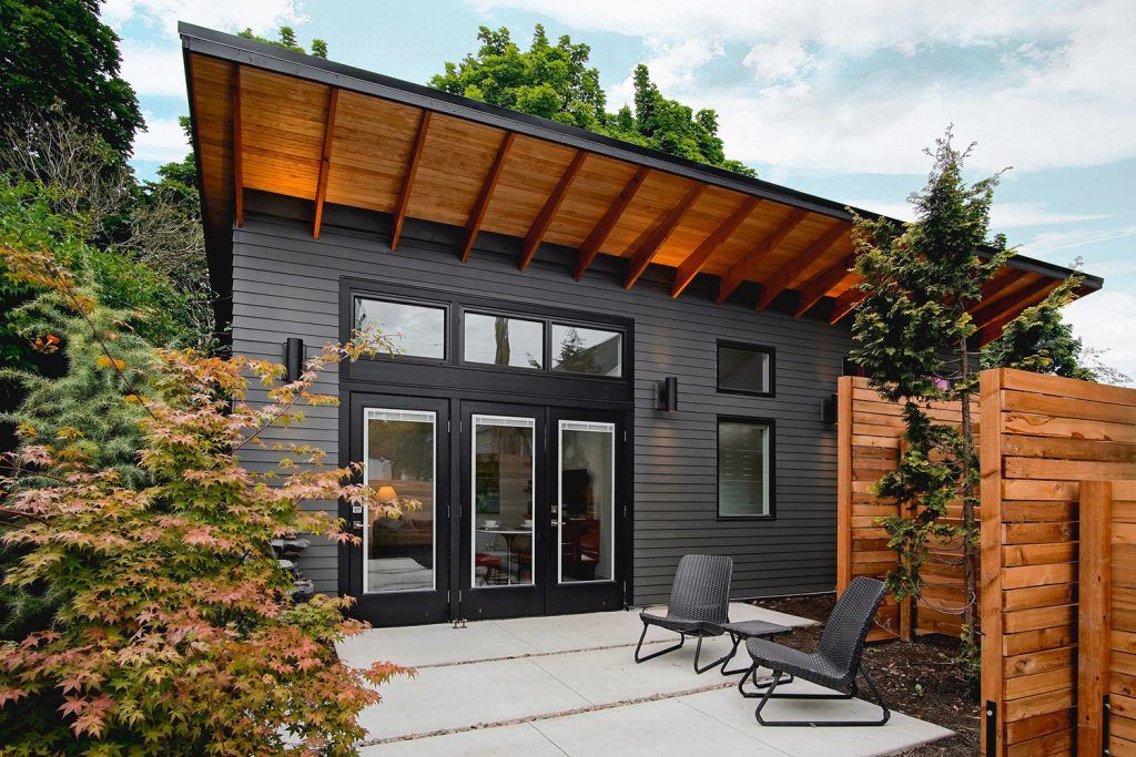 A modern-style grey and wood-toned accessory dwelling unit (ADU) with 3 large vertical and 3 horizontal windows