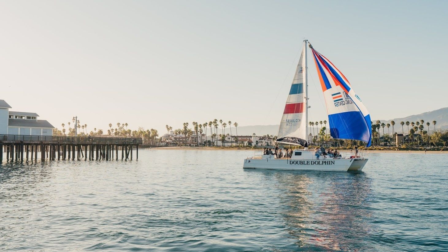 Sailboat with red, white, and blue sails on the water in Santa Barbara Harbor