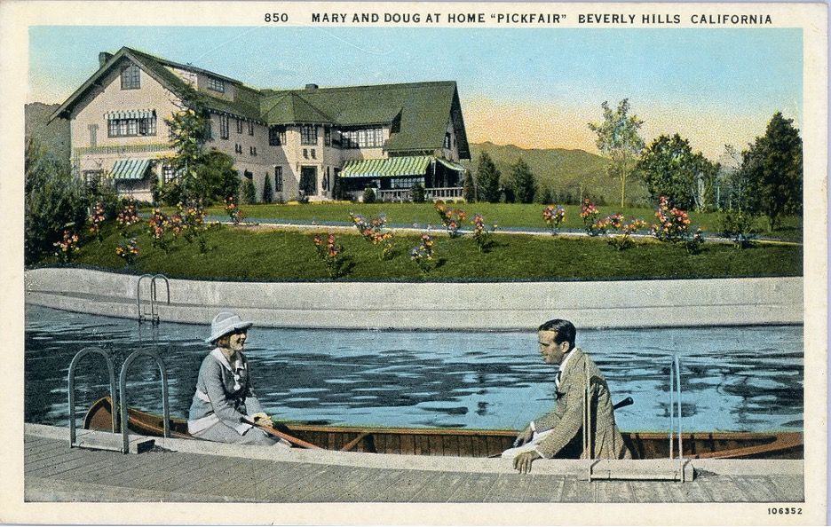 Vintage postcard featuring Mary Pickford and Douglas Fairbanks in a rowboat in the pool of Pickfair, their Beverly Hills home