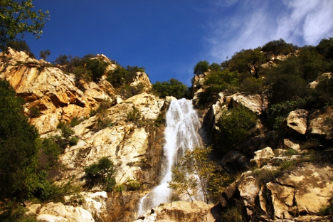 Looking up from the base of Tangerine Falls near Santa Barbara, with water flowing over a precipice and down a rugged rock face.