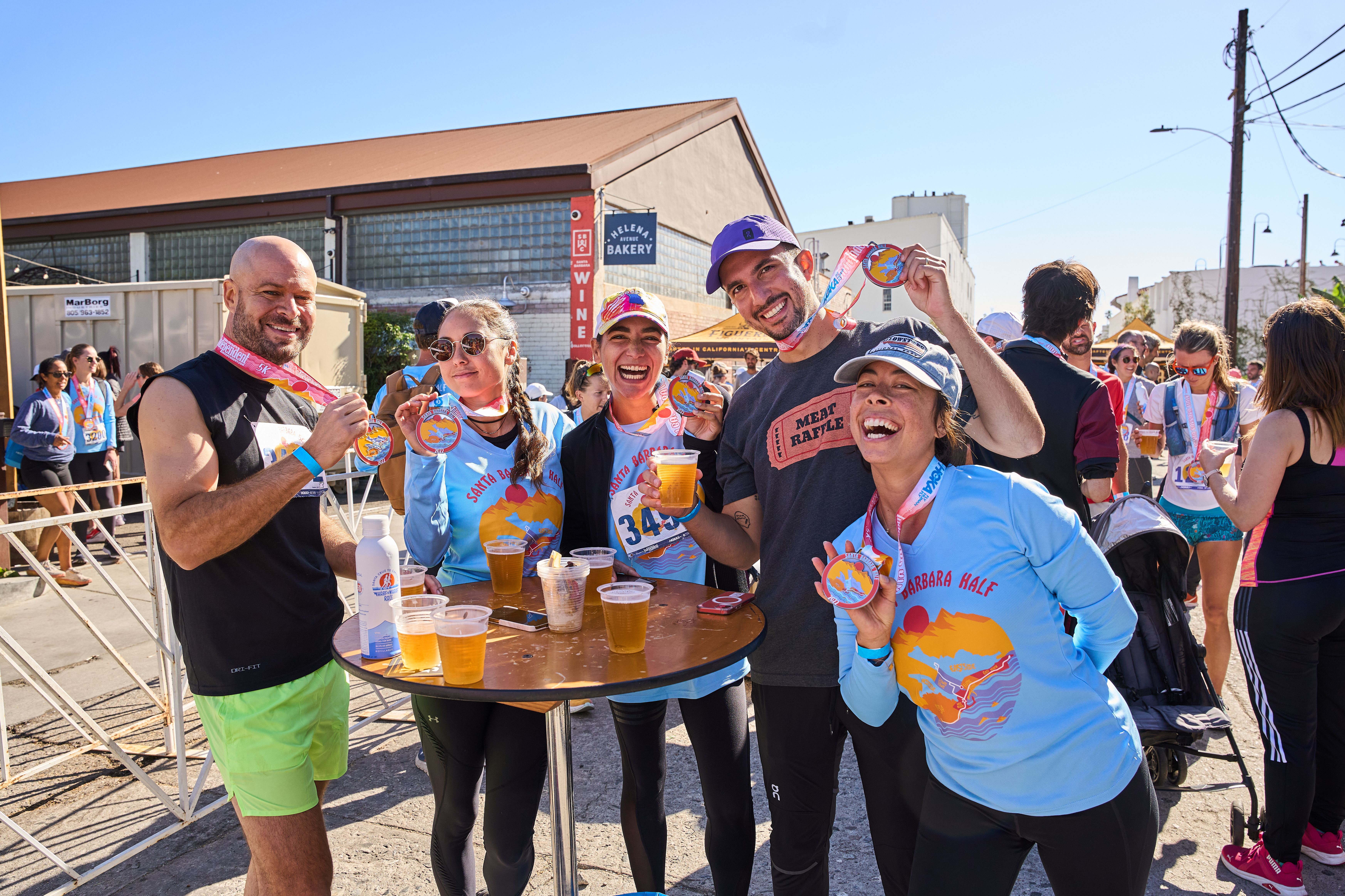 A group of people laughing and drinking beer during a post-marathon party.