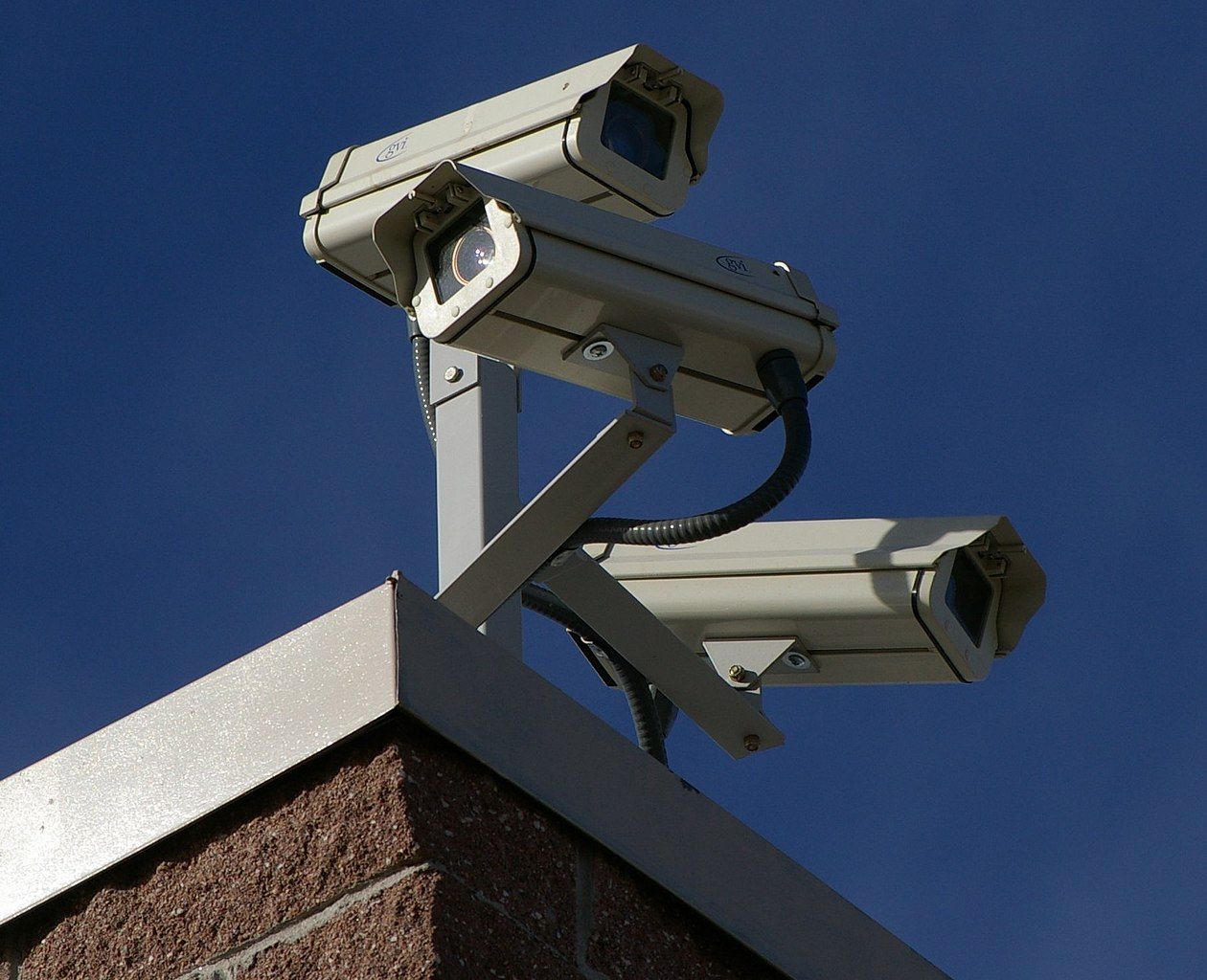 Three surveillance cameras on the roof of a home.