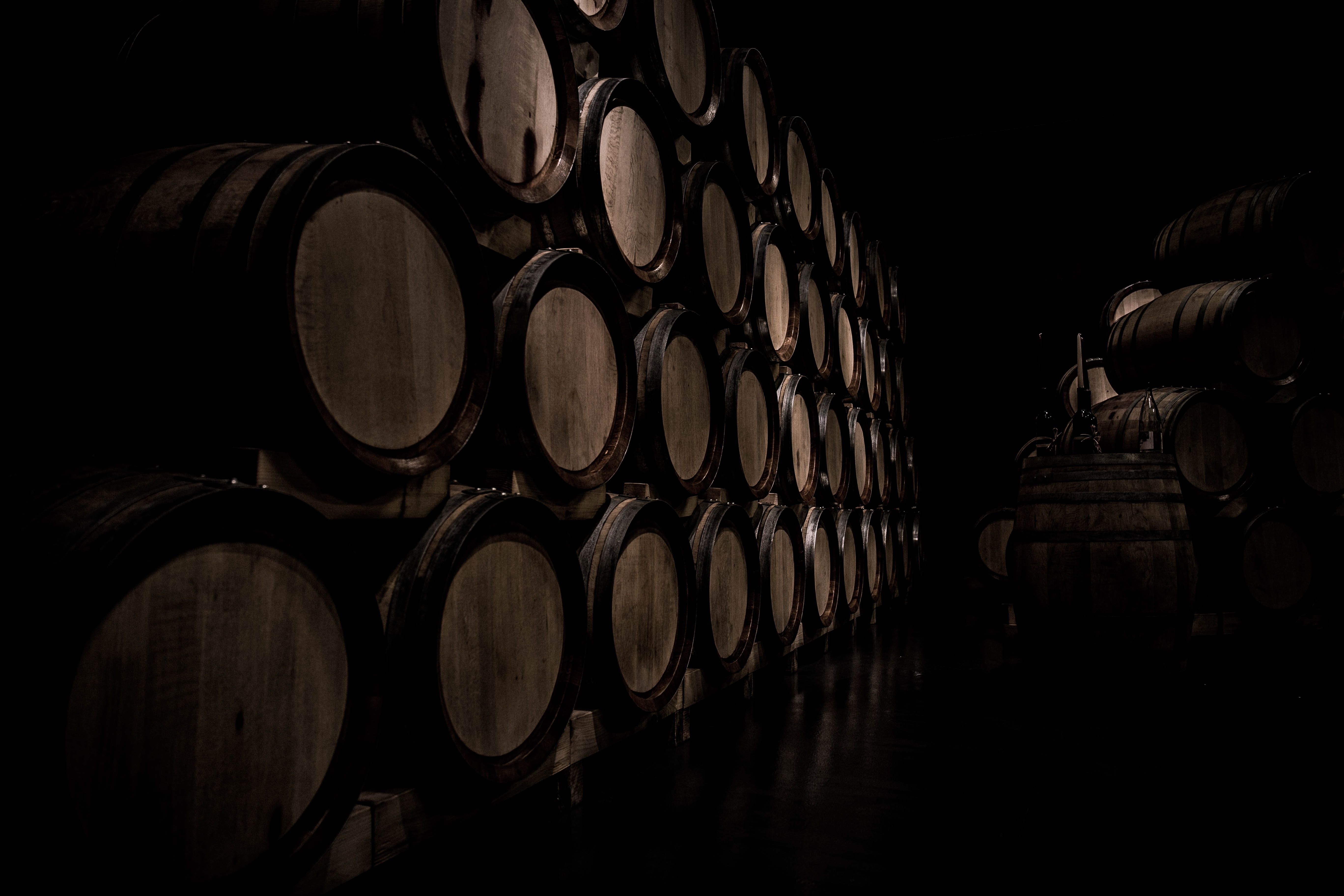 Stacked barrels deep inside a dark wine cellar