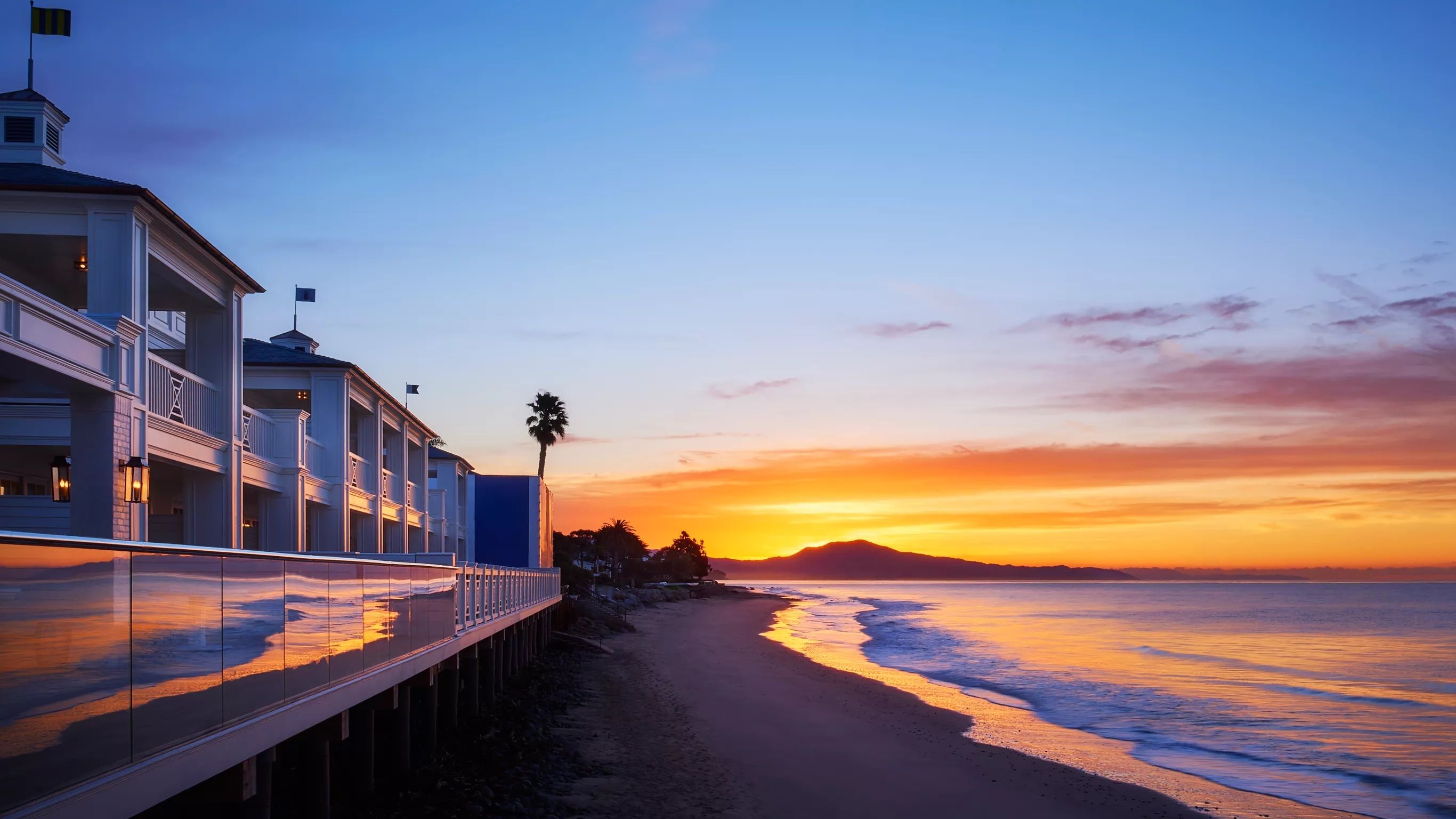 Rosewood Miramar Beach resort buildings on the beach, with a stunning sunset in the background