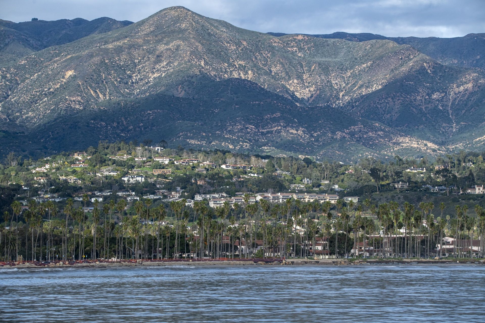 A view of Santa Barbara from the ocean with homes in the foreground and majestic mountains in the background