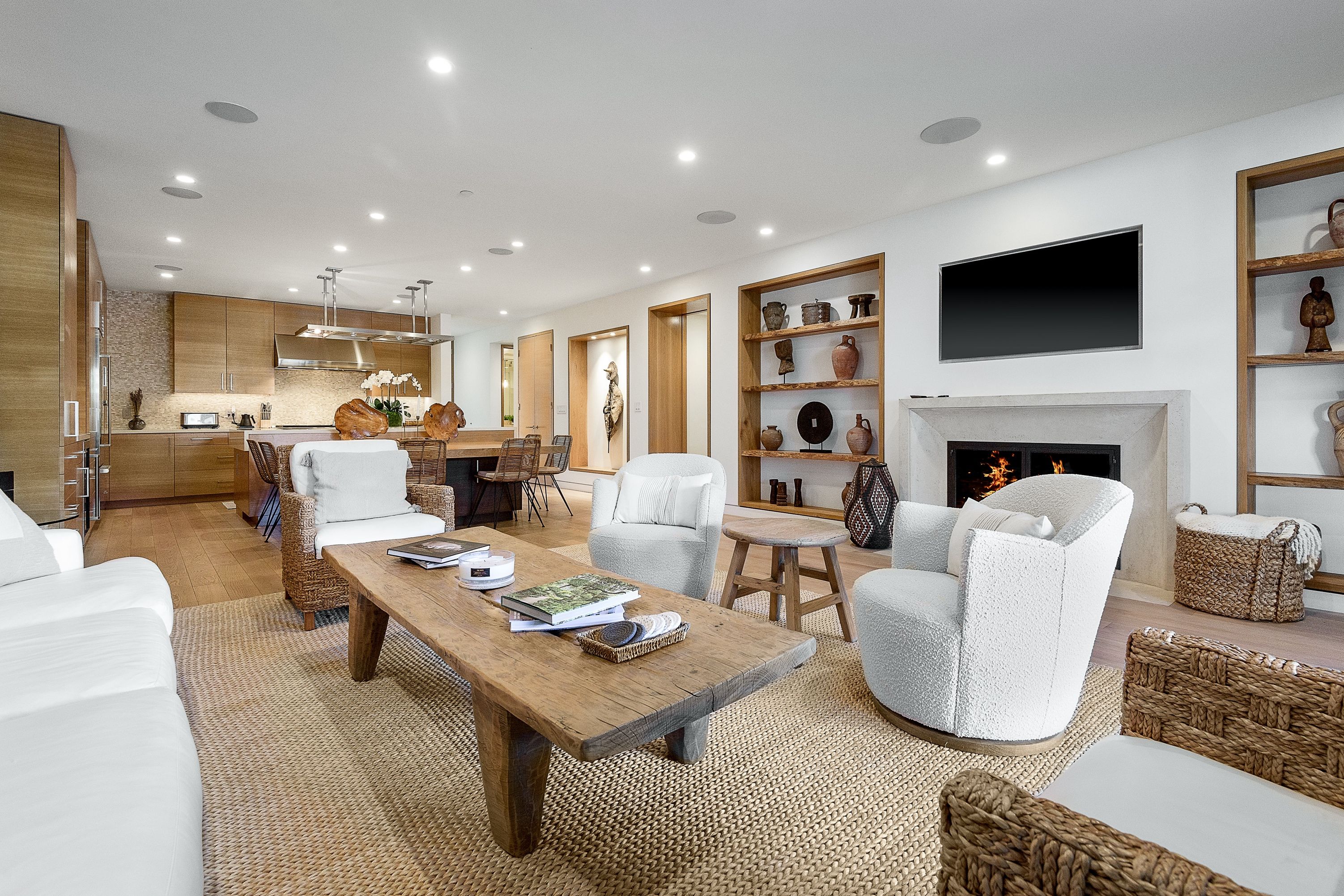 A smartly furnished great room in an upscale mid-century home, with a sleek, open kitchen at its far end.