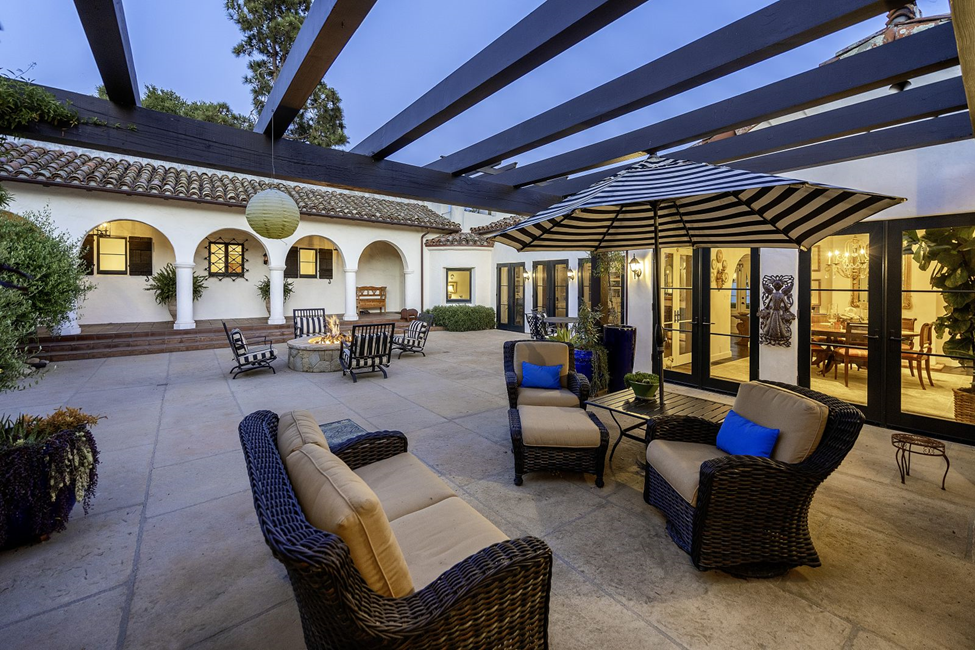 The romantic courtyard of a large hacienda style home, with multiple arches and doors into the residence.