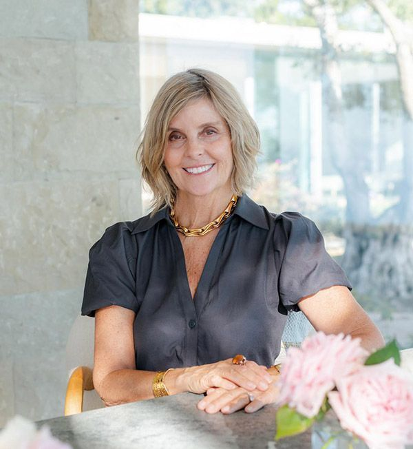 Top luxury Realtor Cristal Clarke, smiling and sitting behind a desk with flowers in the foreground.