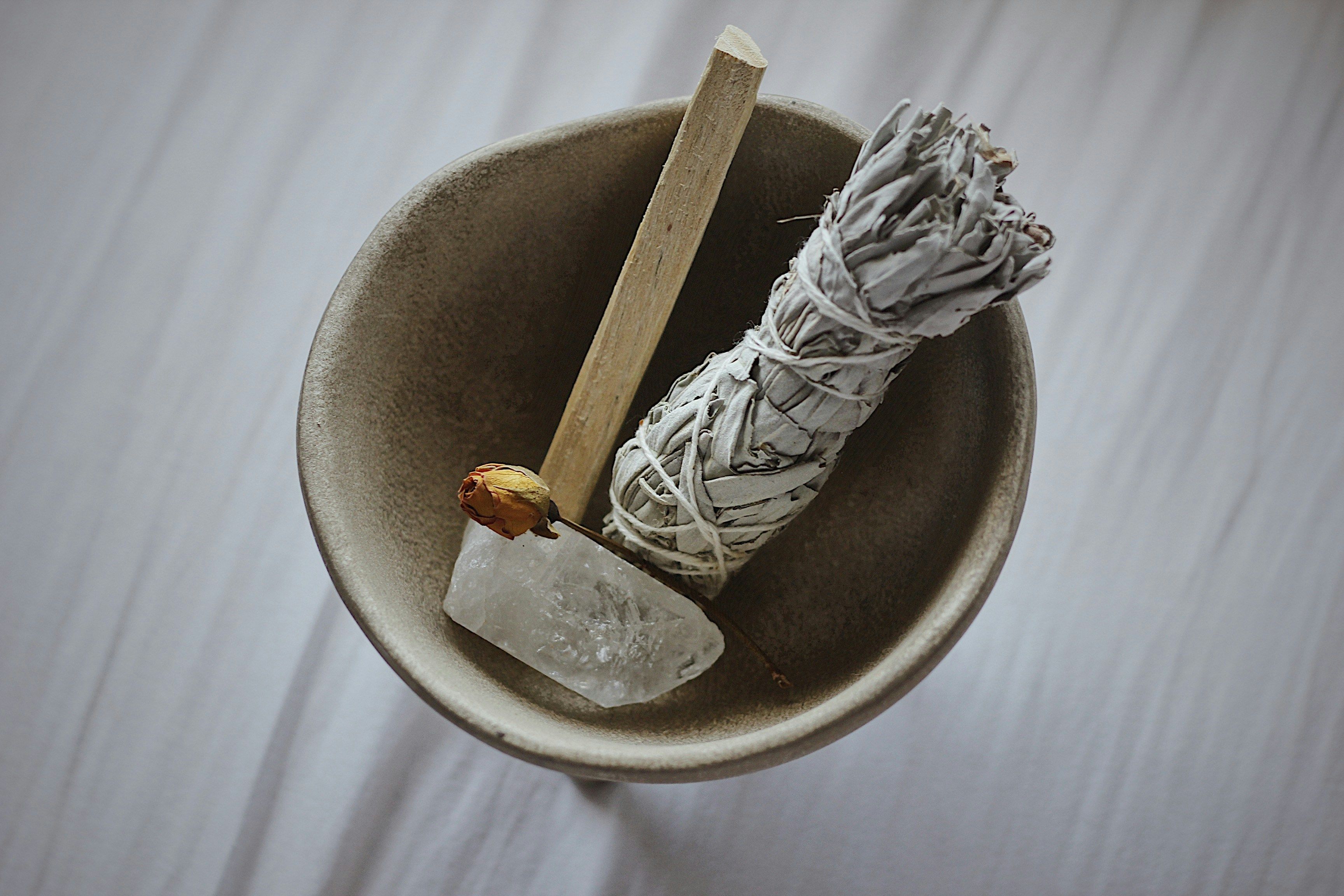 A bowl with a tied bundle of sage and a cristal