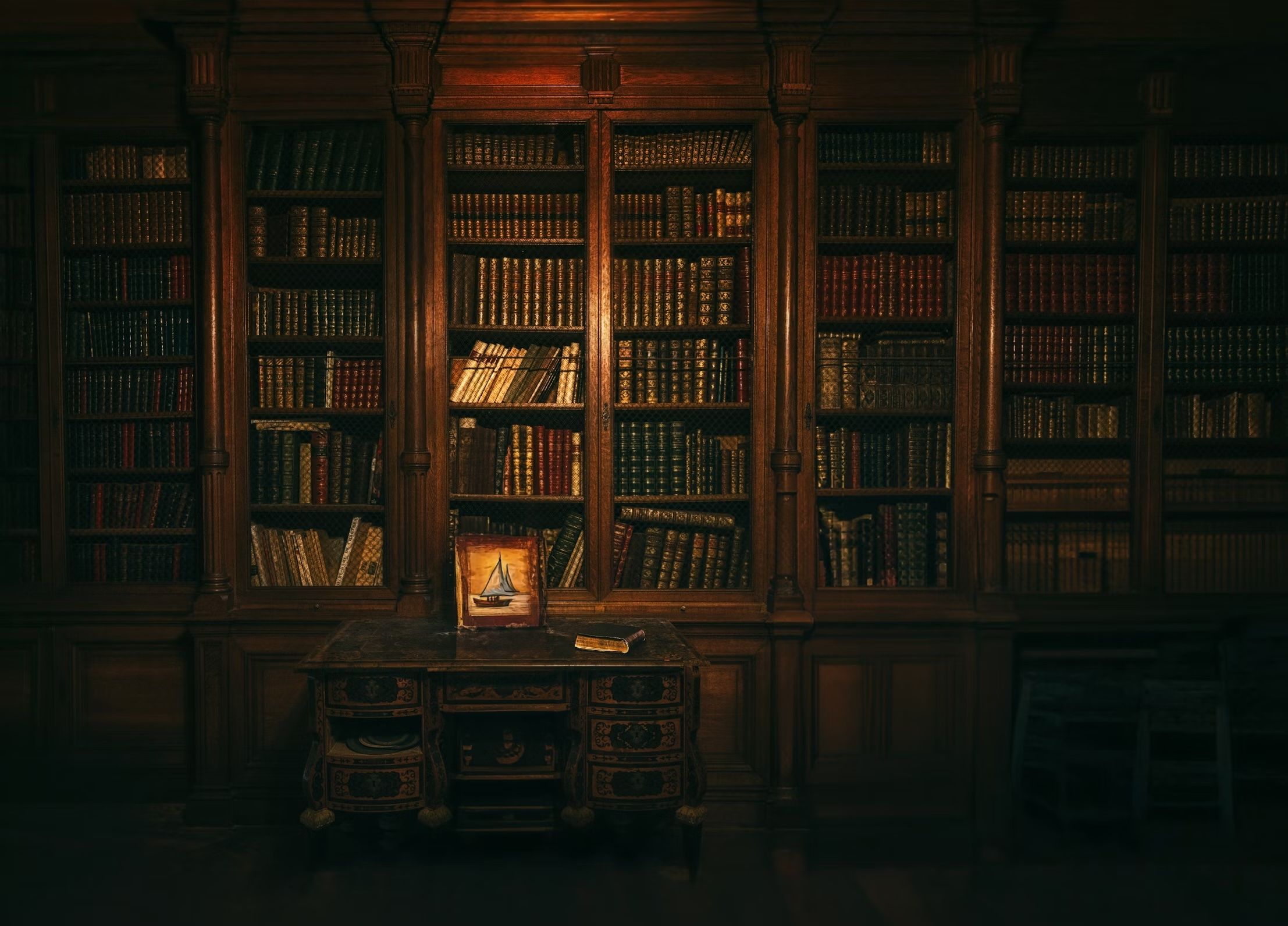 A dim light on a large bookcase in a dark and damp looking library of a haunted house.