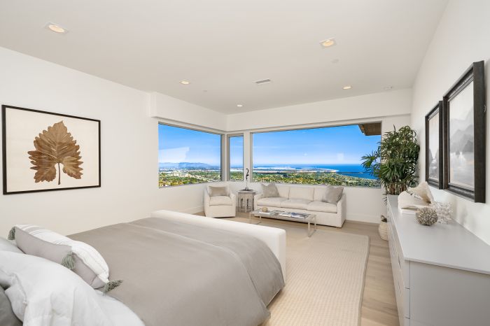 The bedroom of the primary suite in a Ventura home, showing the ocean through an expansive window in a sitting area.